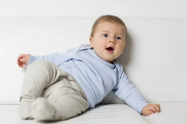 Portrait of lovely smiling baby boy lying on couch. — Stock Photo, Image