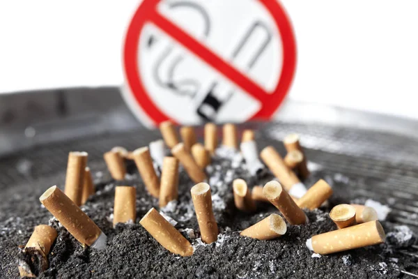 Αποκόμματα τσιγάρων σε τέφρα χωρίς πινακίδα καπνίσματος. — Φωτογραφία Αρχείου