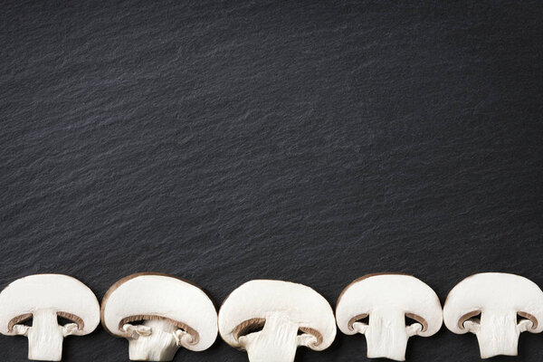 Many champignons framing dark stone copyspace.
