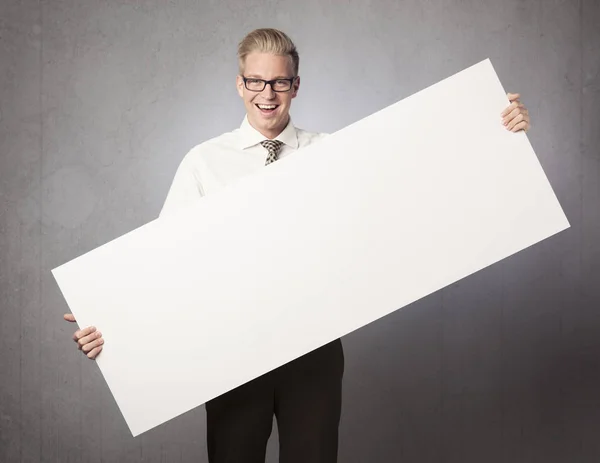 Hombre de negocios alegre que presenta la cartelera blanca en blanco . — Foto de Stock