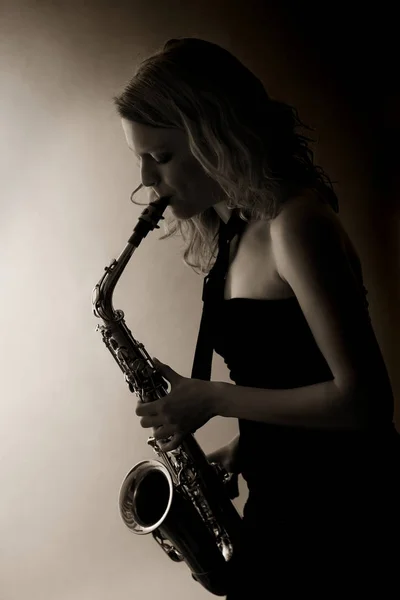 Close-up of woman playing saxophone, sepia toned. Stok Gambar