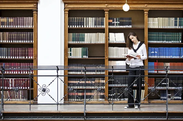 Frau liest vor Bücherregal lizenzfreie Stockfotos