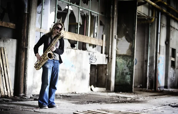Mädchen spielt Saxofon in alter Fabrikhalle. lizenzfreie Stockfotos