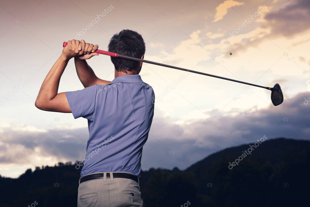 Golfer teeing off at sunset.