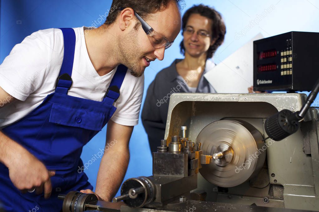 Two technicians on lathe machine in workshop
