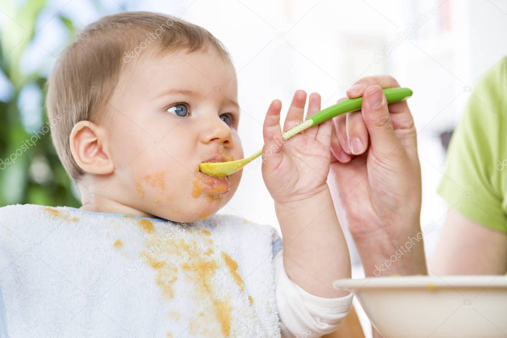 Close up of cute messy baby boy eating his meal.