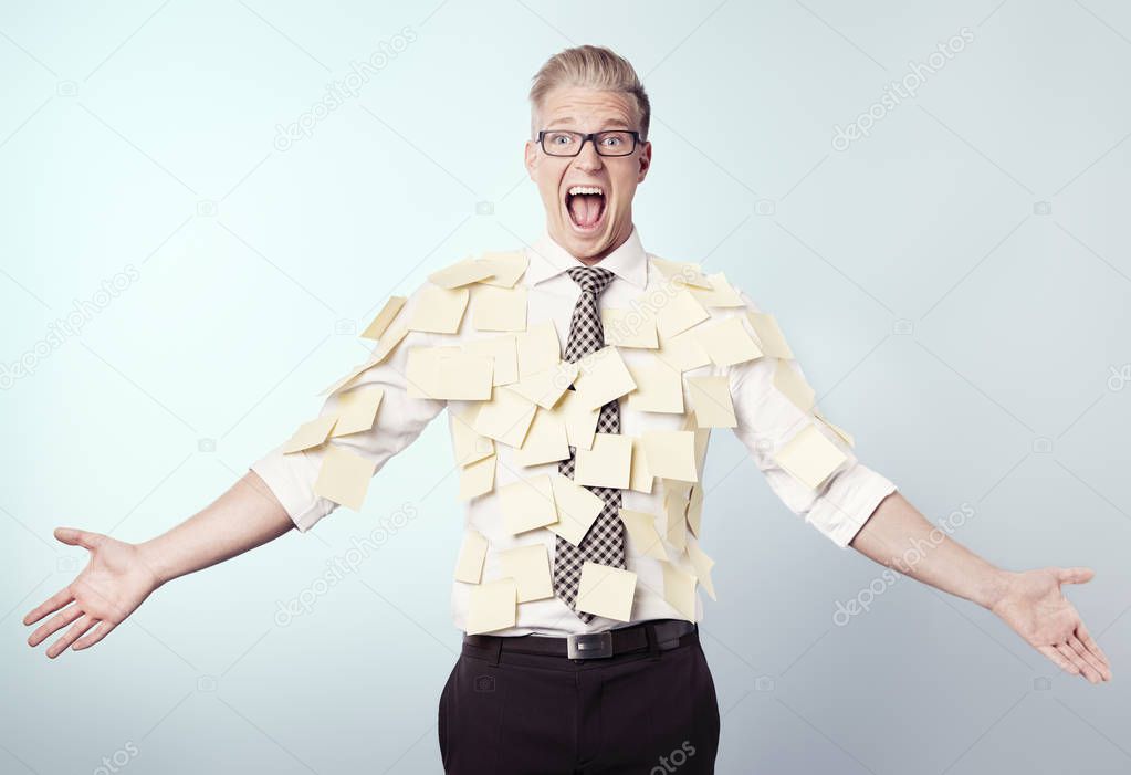 Frustrated businessman covered by blank post-it notes.