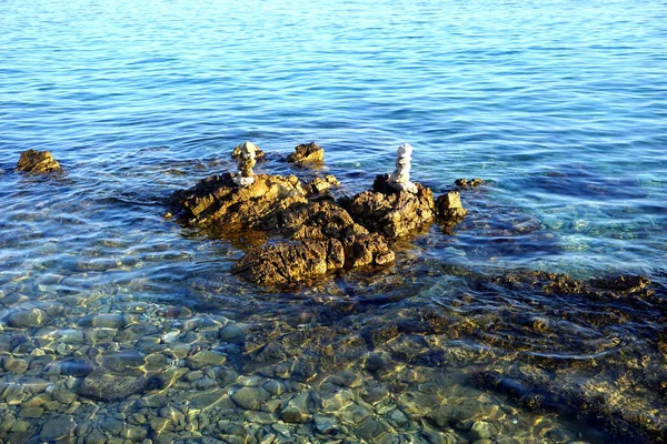 Big stone and pebbles stacked in the shallow sea water on the summer sunny day — Stock Photo, Image