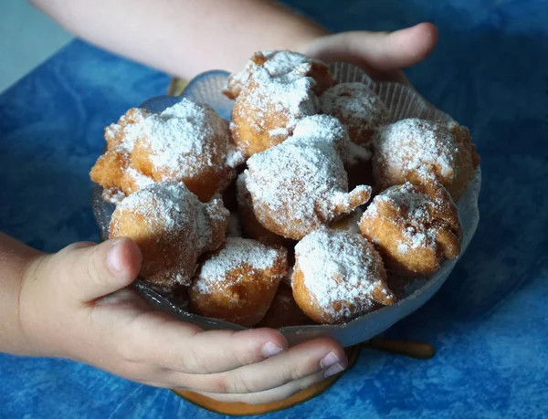 Kinderhände mit einer Schüssel selbstgemachter Fritule, Krapfen, einer Kugel gebratenem Teig. hausgemachte Gebäckkekse — Stockfoto