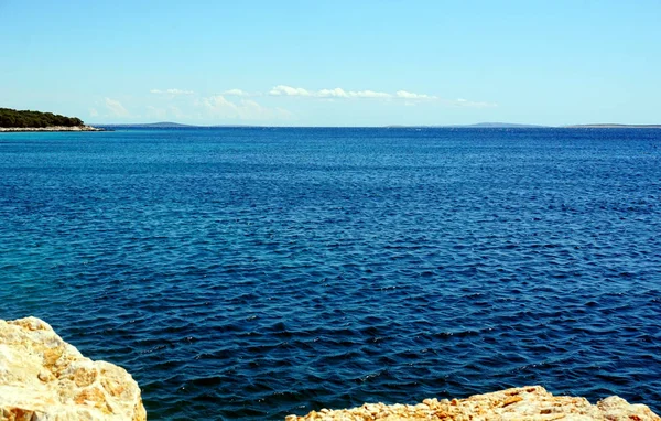 Blue wavy sea surface and horizon line, view from the rocky coast — Stock Photo, Image