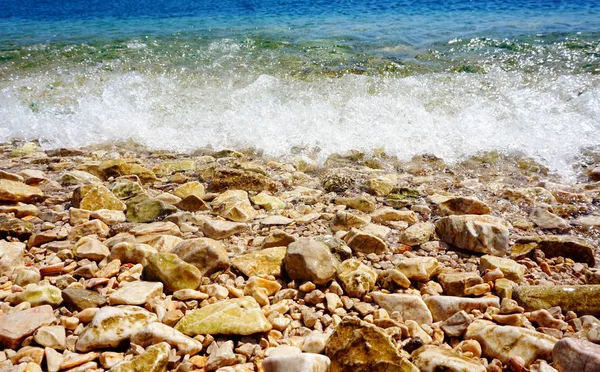 白浪在阳光明媚的一天用鹅卵石在海岸和海滩上飞溅 — 图库照片