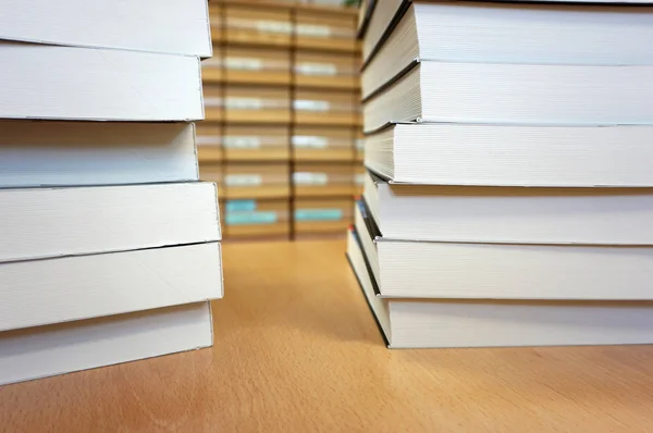 Livros brancos novos empilhados acima na mesa de madeira na biblioteca — Fotografia de Stock