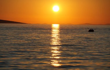 İnanılmaz canlı ve renkli deniz günbatımı kayıkta kürekçilerin silueti