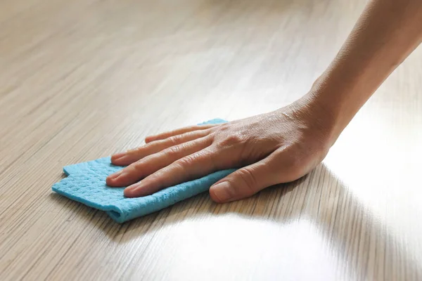 A female hand uses a rag to transform the cleaning product onto the laminate floor. Cleaning concept