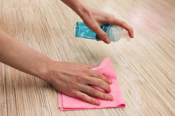 Female hands wash the floor with a rag and spray. Laminate floor cleaning with spray cleaner, cleaning concept. House cleaning