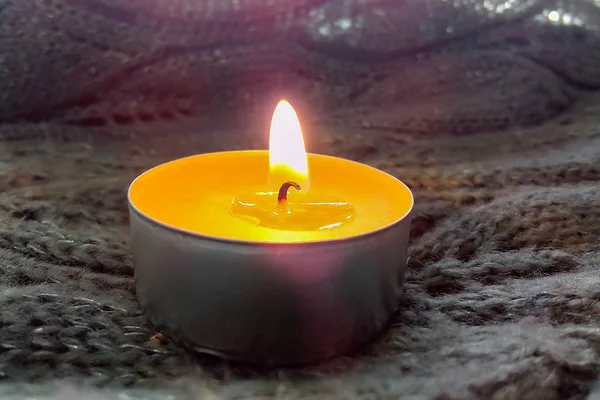 Burning wax candle on a gray warm background, side view. Autumn concept. Spa treatments