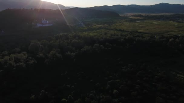 日没時に修道院と山の谷の村の空中ショット — ストック動画
