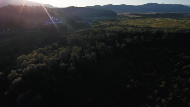 日没時に修道院と山の谷の村の空中ショット — ストック動画