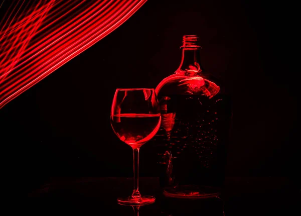 Still life from a glass, bottle, wine, made in the technique of drawing with light