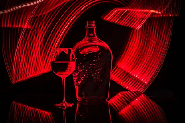 Still life from a glass, bottle, wine, made in the technique of drawing with light
