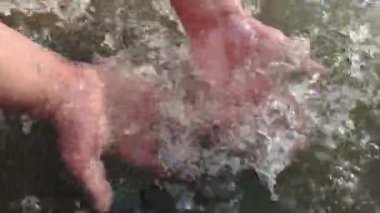 Hızlı bir dağ nehrinde erkek eller