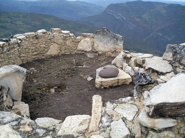 Interior of a circular house on the second level of the fortress of Kuelap, fuller and mortar in the foreground and view of the huge precipices in the Andean mountains