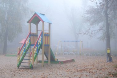 Sisli bir sonbahar sabahında boş çocuk parkı. Sisli bir sabahta şehir parkı