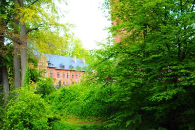 Yeşil ağaçların arkasındaki kırmızı tuğla dansı (Belçika)