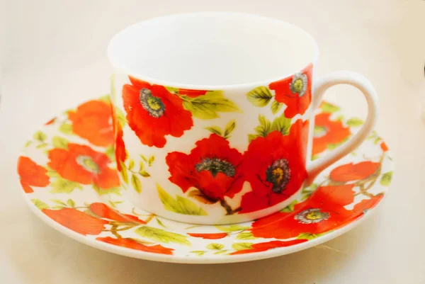 Tea cup with red poppies on a white background.