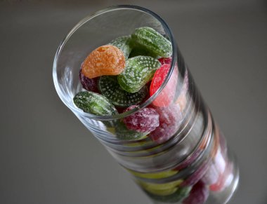 Ayna üzerinde bir cam fincan çok renkli lezzetli şekerler. Cam ve tatlıların yansıması hacim çarpıcı bir etki yaratır ve tatlılar görünüm olarak çok lezzetli kılan çerçeve, nesnelerin sayısını artırır.