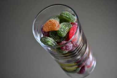 Ayna üzerinde bir cam fincan çok renkli lezzetli şekerler. Cam ve tatlıların yansıması hacim çarpıcı bir etki yaratır ve tatlılar görünüm olarak çok lezzetli kılan çerçeve, nesnelerin sayısını artırır.