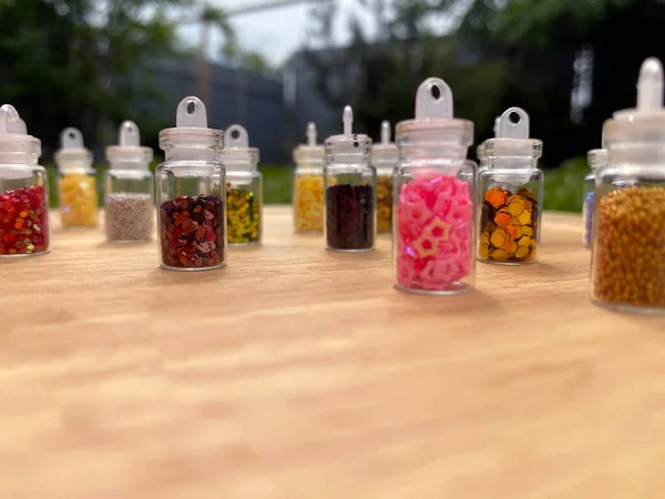 Colorful glitters for nail art and makeup in small glass jars isolated. Fashion and beauty concept, natural background