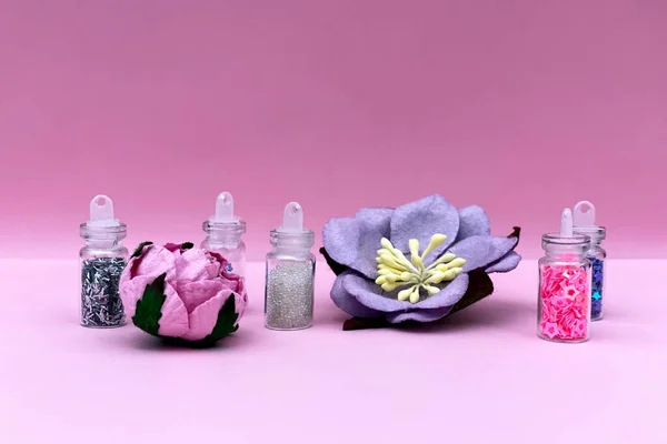 Küçük cam kavanozlarda çivi sanatı ve makyaj için renkli simler. Moda ve güzellik konsepti, pembe arka plan