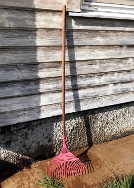 Evin ahşap duvarını tırmıkla. Bahçe araçları.