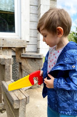Çocuk el testeresi kullanmayı öğreniyor. Eğitim oyunları konsepti. Renkli testere.
