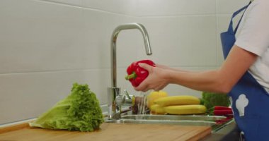 Yakın plan çekim. Kadınların elleri lavaboda büyük bir kırmızı biberi yıkıyor. Yandan ateş ediyorlar. 4k