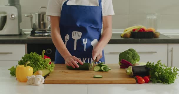 Une femme tranche du concombre sur le tableau de la cuisine. Préparation des salades. 4k — Video