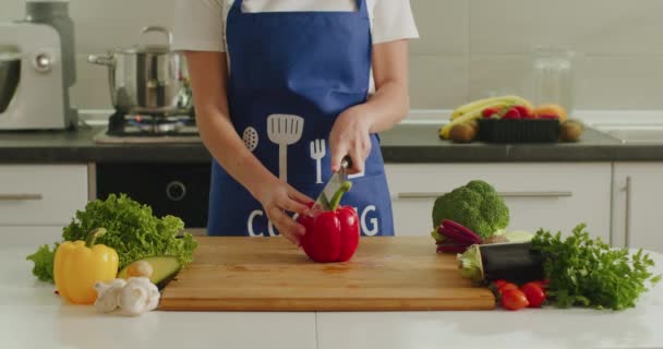 Une femme coupe un gros poivre sur la planche de la cuisine. Préparation des salades. 4K — Video