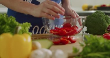 Yakın plan çekim. Kadın eli, domates ve biberi bir kaseye koyuyor. 4K