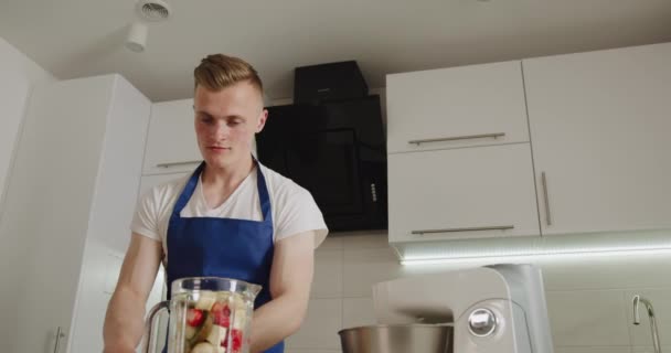 Ein Mann füllt eine Mixer-Schüssel mit Früchten und legt sie auf den Mixer. Smoothies machen. 4K — Stockvideo