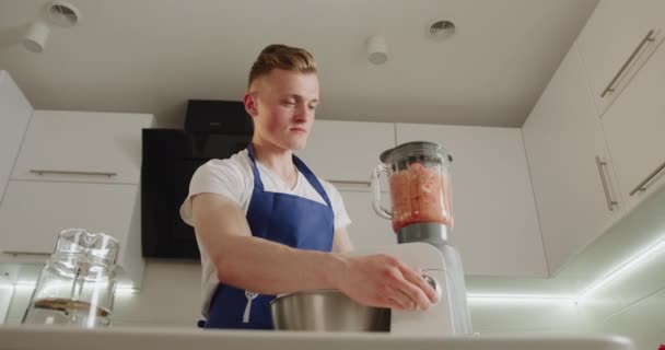 De man start de blender en mengt het fruit. smoothies maken. 4K — Stockvideo