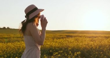 Gülümseyen bir kız telefonda konuşuyor ve sevinçten hoplayıp zıplıyor. Sarı tarlada bir kız yürüyor. Gün batımı. 4k