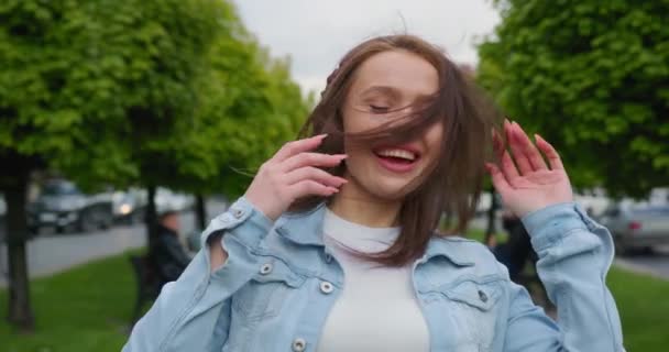 Het meisje gaat de steeg in en danst. Ze lacht en luistert naar muziek met grote koptelefoons. Haar haar fladdert in de wind. 4K — Stockvideo