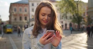 Kız mesajı alıyor ve gülmeye başlıyor. Saçları rüzgarda dalgalanıyor. Yaz güneşi parlıyor. 4K