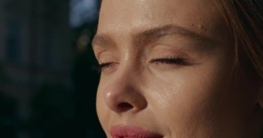 Yakın plan çekim. Kız gözlerini açıyordu. Güneş onun yüzünde parlıyor. 4K