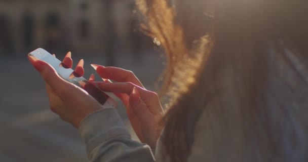 Een close-up opname. Het meisje sms 't aan de telefoon. Haar haar fladdert in de wind. 4K — Stockvideo