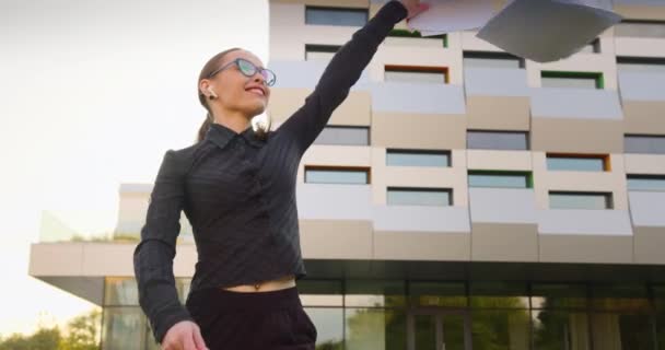 Une femme d'affaires va jeter des documents de travail autour. Elle est heureuse et souriante. 4k — Video