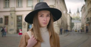 Yakın plan çekim. Kız, kameraya bakıyor. O, torbayı elinde tutuyor. Yağmur damlaları yanından uçup gidiyor. 4K