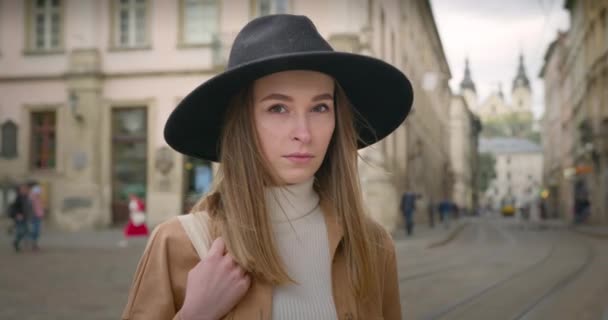 Penembakan jarak dekat. Gadis itu melihat ke arah kamera. Dia memegang tas di tangannya. Raindrops terbang melewatinya. 4K — Stok Video