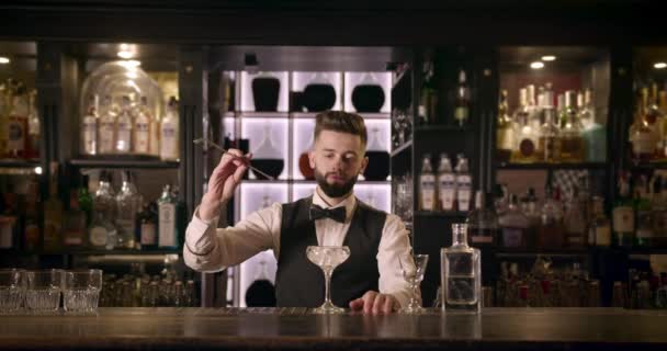 Profesionální barman dělá nějaký trik s dlouhou lžičkou a obrací led ve sklenici. 4k — Stock video